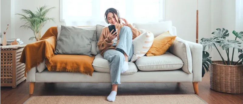 Happy asian woman listening to music from mobile phone